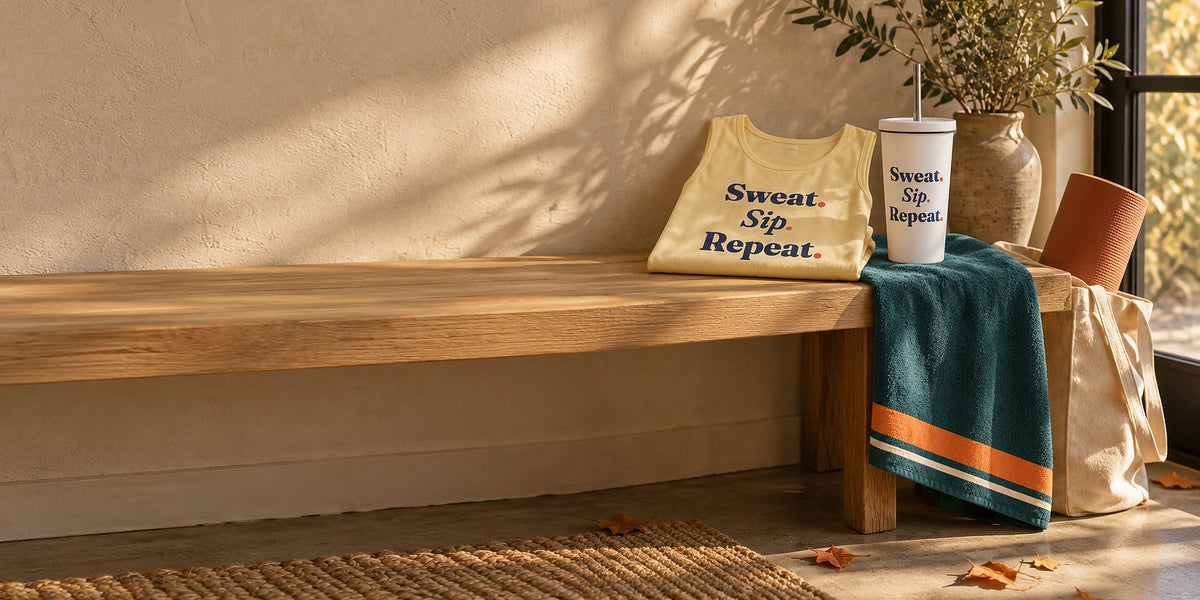 Butter tank, white tumbler and teal sweat towel on a sunlit studio bench in early fall