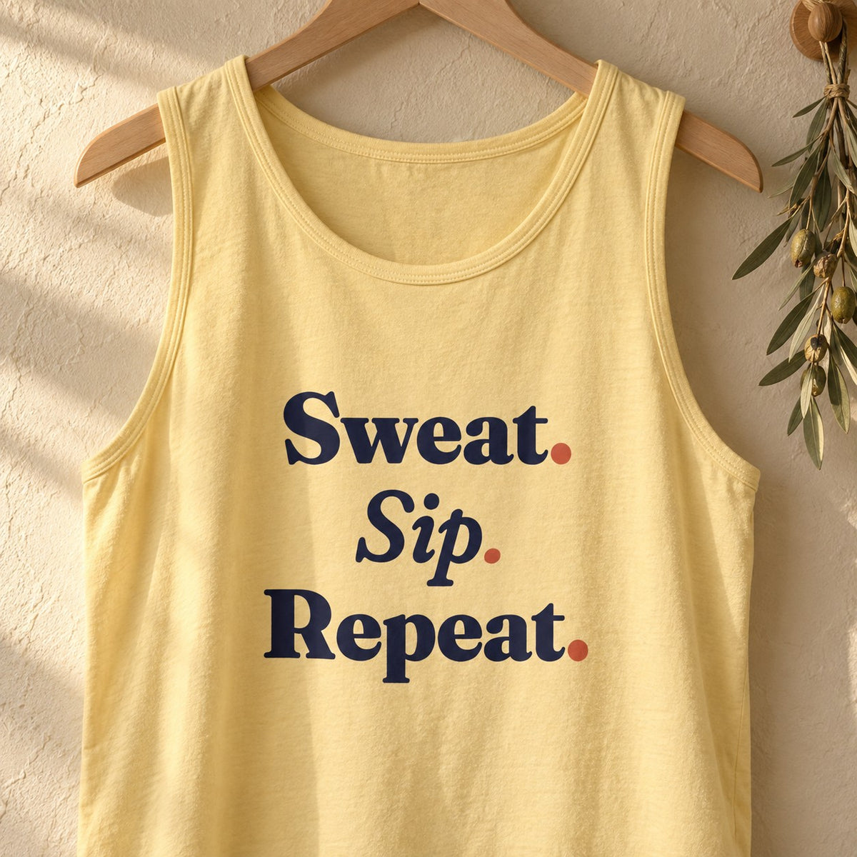 Sweat. Sip. Repeat. Garment-Dyed Tank, Butter print close-up on a hanger (lifestyle)